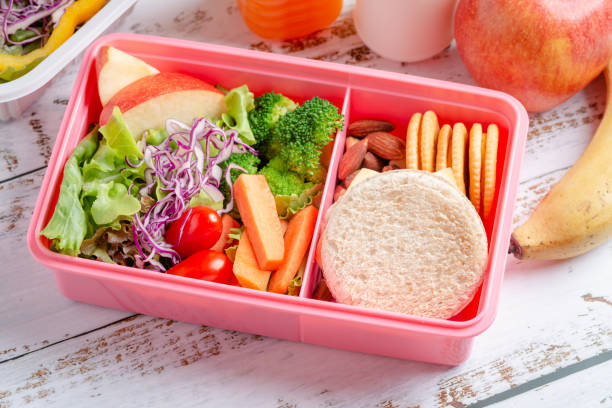 クラッカーとサラダを入したサンドイッチチーズ、バナナとリンゴ、オレンジジュース、ミルクのヘルシーなランチボックスセット。 - lunch box packed lunch school lunch lunch ストックフォトと画像