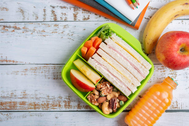 coffret-déjeuner sandwich au jambon avec carotte et noix mélangées, pomme en boîte, banane et pomme au jus d'orange. kid bento pack pour l'école. vue du haut et espace de copie. - lunch packed lunch lunch box apple photos et images de collection