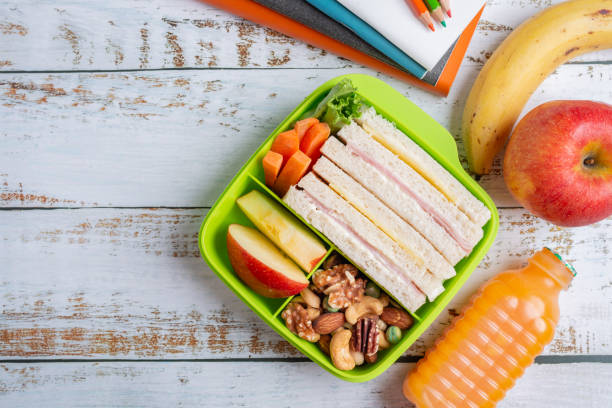 Lunch box set of Ham cheese sandwich with carrot and mixed nuts, apple in box, banana and apple with orange juice. Kid bento pack for school. Top view and Copy space. Lunch box set of Ham cheese sandwich with carrot and mixed nuts, apple in box, banana and apple with orange juice. Kid bento pack for school. Top view and Copy space. lunch box photos stock pictures, royalty-free photos & images