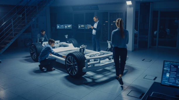 istock Team of Automotive Engineers Working on Electric Car Platform Chassis, Taking Measures, working with 3D CAD Software, Analysing Efficiency. Vehicle Frame with Wheels, Engine and Battery. 1162762233