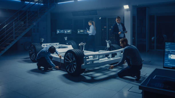 istock Team of Automotive Engineers Working on Electric Car Platform Chassis, Taking Measures, working with 3D CAD Software, Analysing Efficiency. Vehicle Frame with Wheels, Engine and Battery. 1162762292