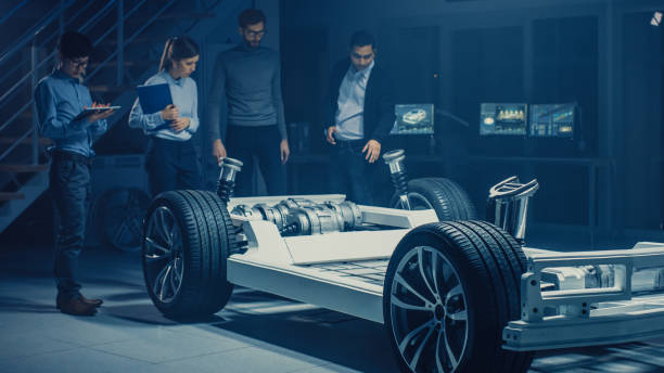 istock Team of Automotive Engineers Discussing and Designing Electric Car Platform Chassis Prototype, Taking Measures, Working with 3D CAD Software, Checking Quality Control. Vehicle Frame with Wheels, Engine and Battery. 1162762340