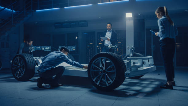 istock Team of Automotive Engineers Working on Electric Car Platform Chassis, Taking Measures, working with 3D CAD Software, Analysing Efficiency. Vehicle Frame with Wheels, Engine and Battery. 1162762341
