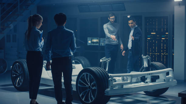 istock Team of Automotive Engineers Working on Electric Car Chassis Platform, Taking Measures, working with 3D CAD Software, Analysing Efficiency. Vehicle Frame with Wheels, Engine and Battery. Elevated Shot 1162762397