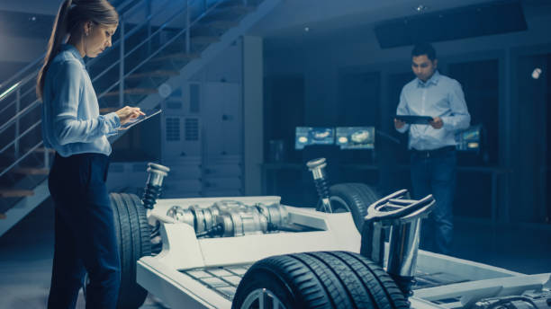 istock Team of Automotive Engineers Working on Electric Car Chassis Platform, Taking Measures, working with 3D CAD Software, Analysing Efficiency. Vehicle Frame with Wheels, Engine and Battery 1162762453