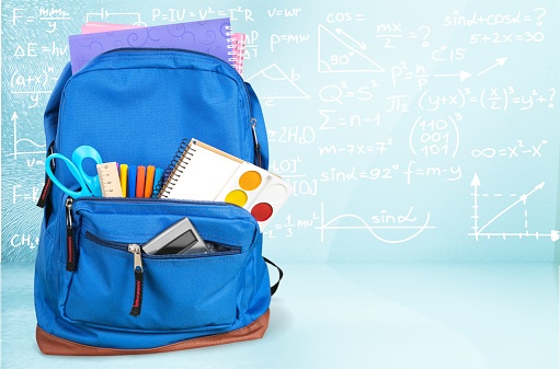 School Backpack with stationery on wooden table