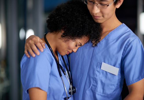 Shot of a medical practitioner consoling an unhappy colleague in a hospital