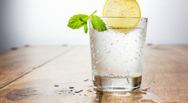 Copy space - glass of sparkling water on a table with a lemon and a mint Copy space - glass of sparkling water on a table with a lemon and a mint carbonated water photos stock pictures, royalty-free photos & images