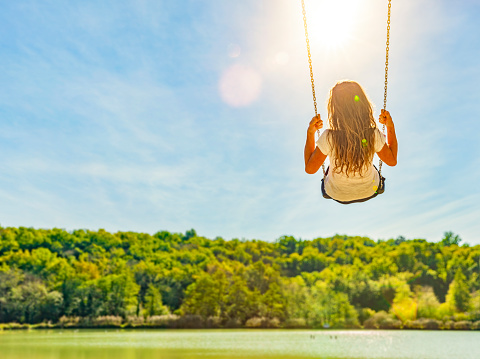 Woman on a swing at a lake with sandy beach