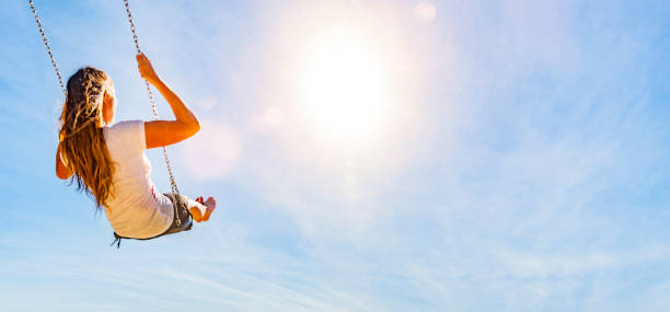 istock Woman on a swing with blue sky 1162786056
