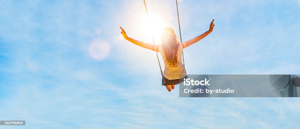 Woman on a swing with blue sky Woman on a swing with blue sky in the back light Women Stock Photo