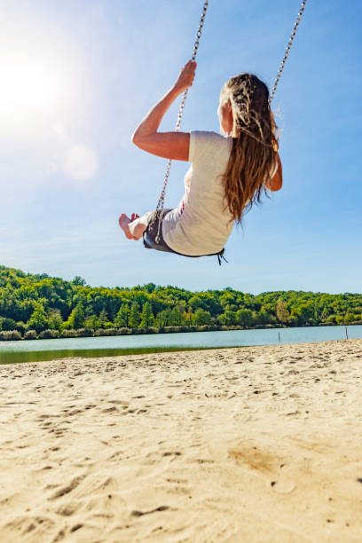 istock Woman on a swing at a lake 1162786827