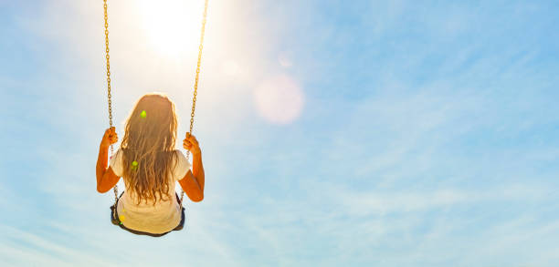 istock Woman on a swing with blue sky 1162786832