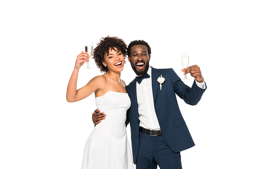 happy african american bride and bridegroom holding champagne glasses isolated on white