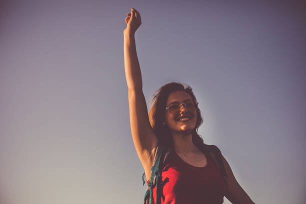istock Happy young woman hitchhiking while going on a camping adventure 1162790368