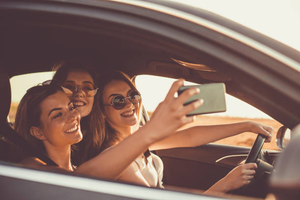 istock Three cheerful young women taking a selfie while driving in the car 1162791654