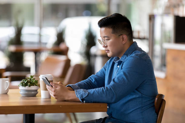 istock Man uses smartphone in coffee shop 1162793100