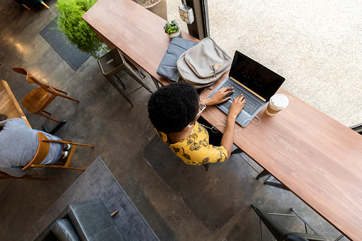 High angle view of a young African American woman using laptop while in coffee shop.