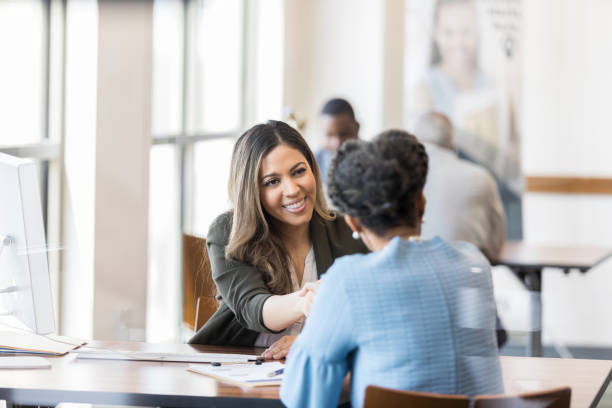 When the loan is processed, bank manager shakes customer's hand After the loan is successfully processed, the bank manager shakes her customer's hand. bank manager stock pictures, royalty-free photos & images