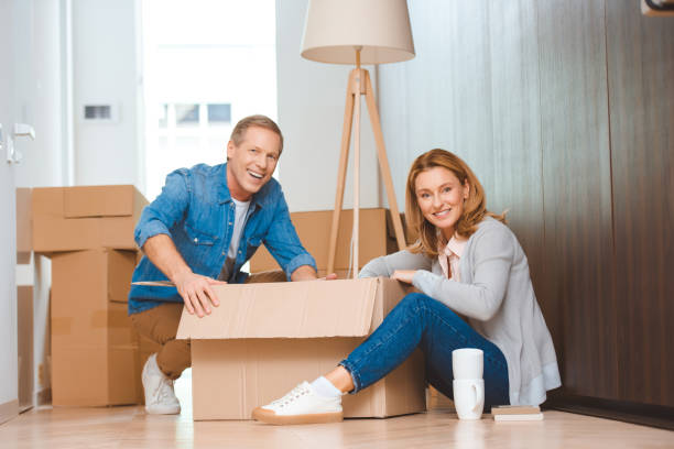 istock happy couple sitting on floor and unpacking cardboard box 1162802540