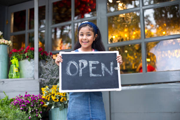 girl holding open sign at flower shop - florist flower market flower store imagens e fotografias de stock