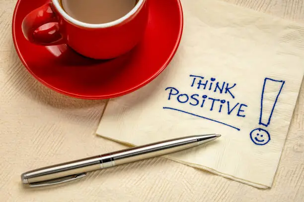 think positive motivational reminder - handwriting on a napkin with a cup of coffee