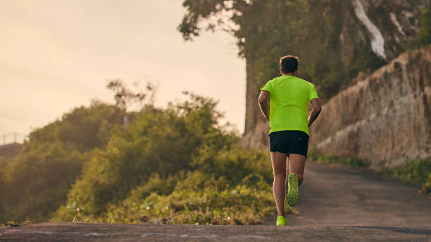 istock Man jogging on a downhill / uphill in suburb mountain road. 1162806360