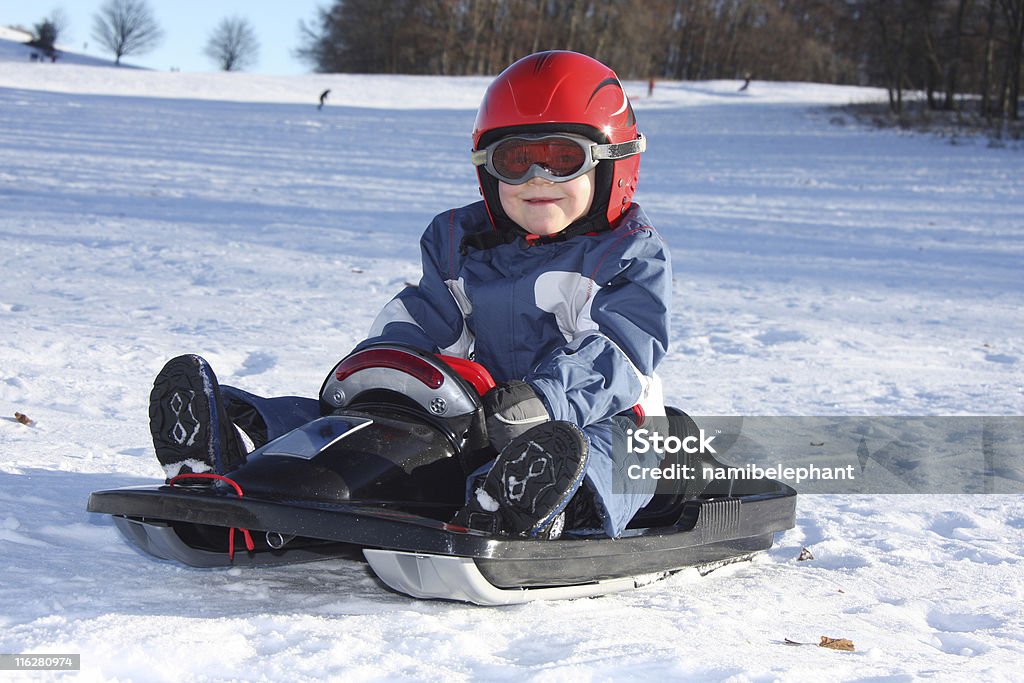young boy sentado en el trineo - Foto de stock de Accesorio de cabeza libre de derechos