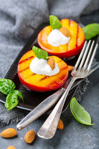 melocotones fritos con yogur, miel y almendras. - dessert grilled peaches peach fotografías e imágenes de stock