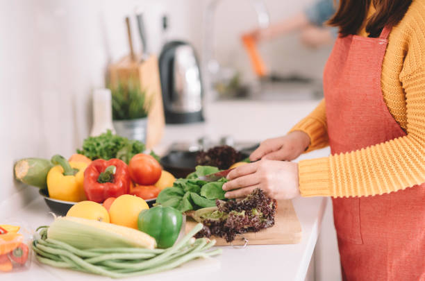 istock young woman cutting vegetables at kitchen 1162810843