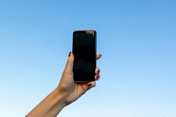 istock Woman hand with modern smartphone on on blue sky. Blank screen smartphone. Mobile communication network, information concept 1162811072