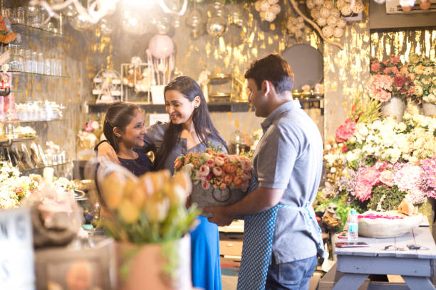 Male florist selling flowers to customers at his flower shop