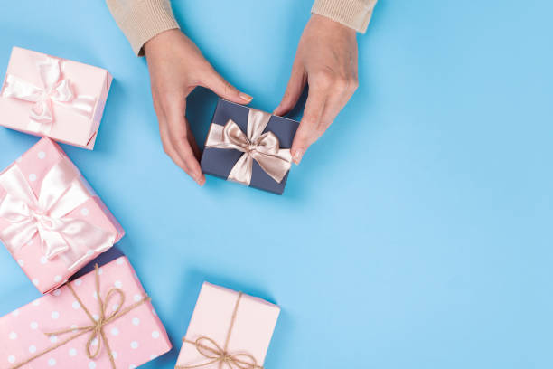 istock Womans hands holding gift or present box on blue pastel table top view. Flat lay  for birthday or New Year. 1162812351