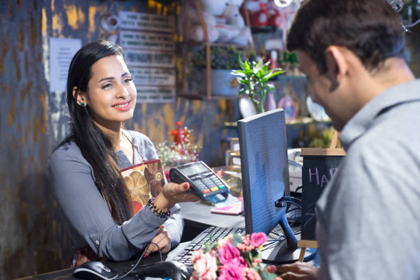 client paying for flowers with credit card - flower computer young women selling imagens e fotografias de stock