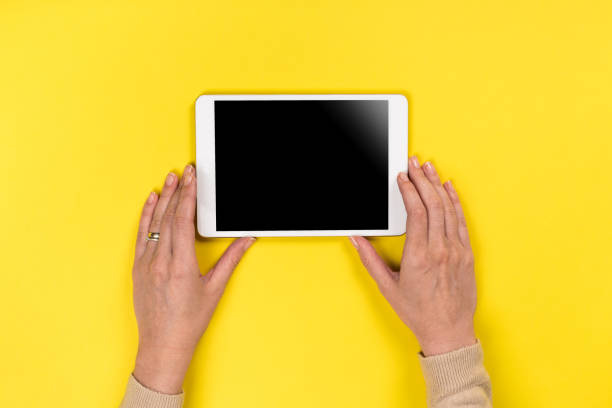 istock Closeup shot of  Woman's hands with perfect manicure  holding tablet, Empty display device. with clipping path. Yellow background 1162812708