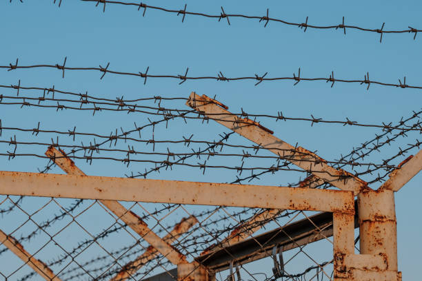istock the barbed wire fence on blue sky background 1162816142