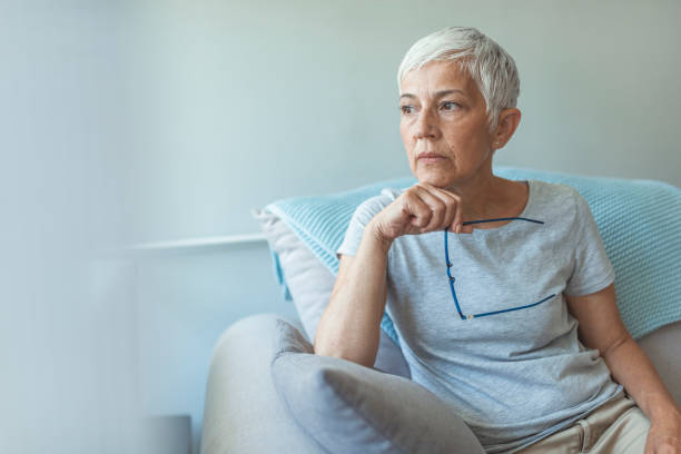 Pensive woman. Feeling Down. Middle aged woman in glasses looking down. Portrait of pensive worried senior woman looking through the window and thinking. Pensive woman. skeptical look stock pictures, royalty-free photos & images