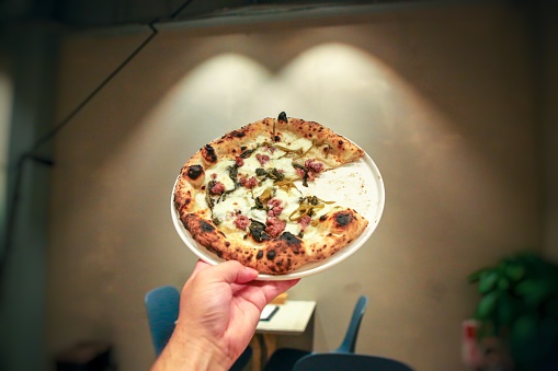 A man is holding pizza on the plate