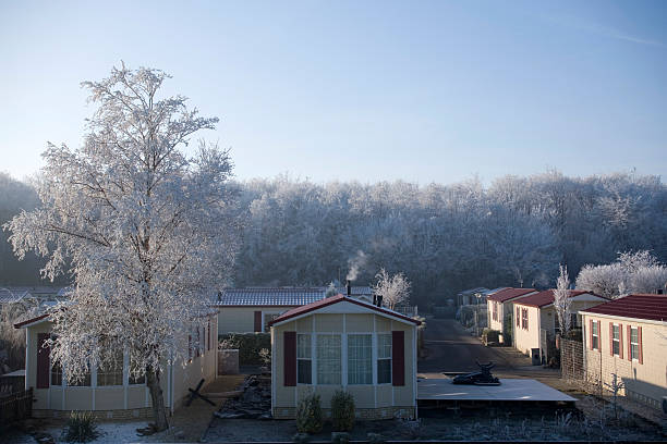 Morning sun rises  and illuminates  bar trees behind a single family home on Cape Cod decorated for Christmas after a light overnight snowfall