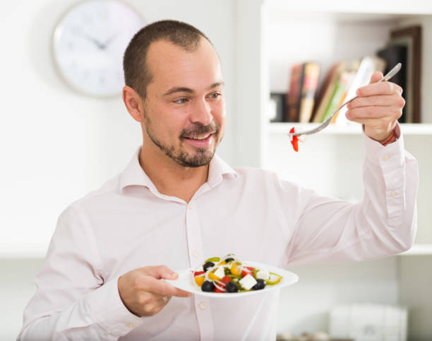 istock Smiling man looking at greek salad 1162822233