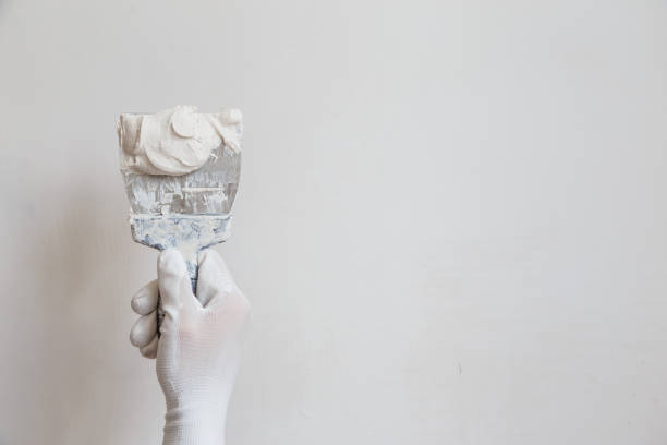 Worker in white gloves performs plastering of the walls of the room. Worker in white gloves performs plastering of the walls of the room hand with a plaster spatula stock pictures, royalty-free photos & images