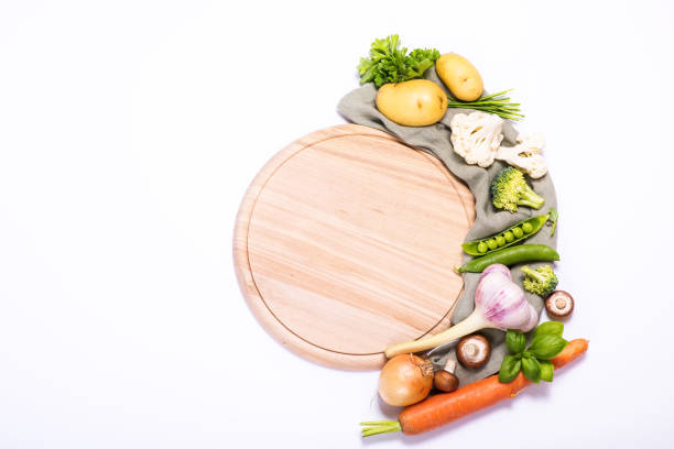 istock Fresh vegetables for cooking around round empty cutting board, ingredients for healthy eating, copy space white background 1162827477