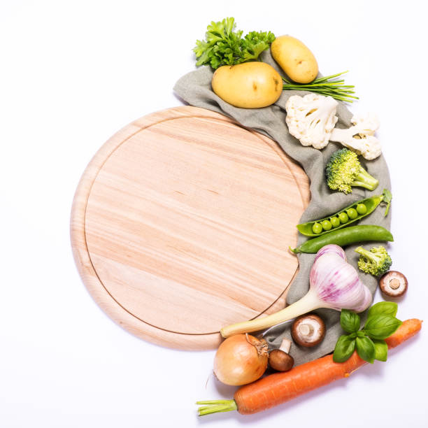 istock Fresh vegetables for cooking around round empty cutting board, ingredients for healthy eating, copy space white background 1162827493