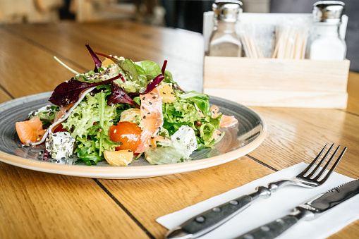 Business lunch salad on plate with fork and knife on the table nobody close-up salt and papper on background blurred