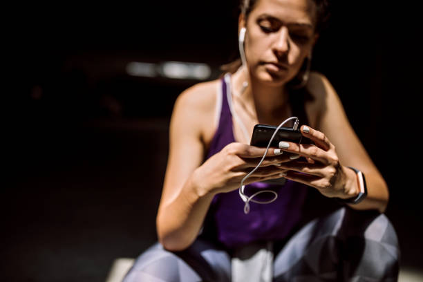 istock Determined female athlete listening music and using smart phone while taking break from running 1162831997
