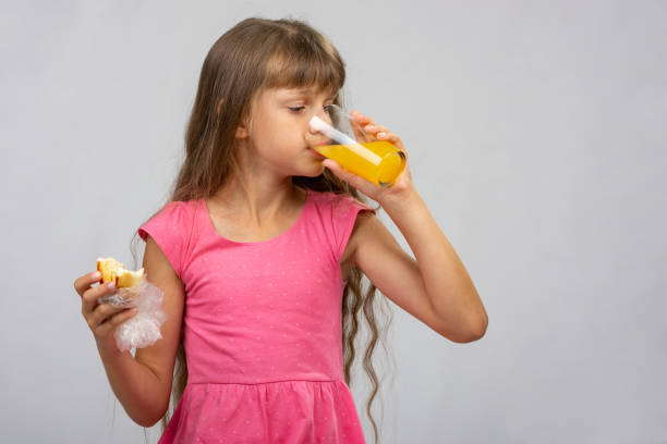 istock A girl drinks orange juice and eats a bun 1162832776
