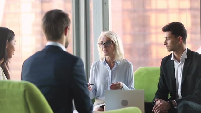 Old businesswoman talking to diverse partners at international business negotiations