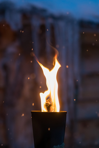 Fire burning inside metal torch in front of a wooden shed in a Sami people village, northern Norway