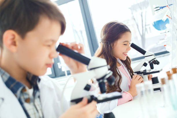 istock Little kids learning chemistry in school laboratory looking in microscopes 1162842433