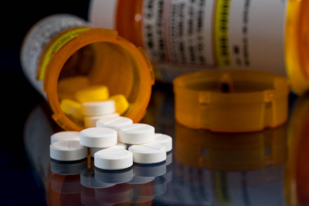 macro de comprimidos opioides de oxicodona con botellas recetadas sobre fondo oscuro - medicamento fotografías e imágenes de stock
